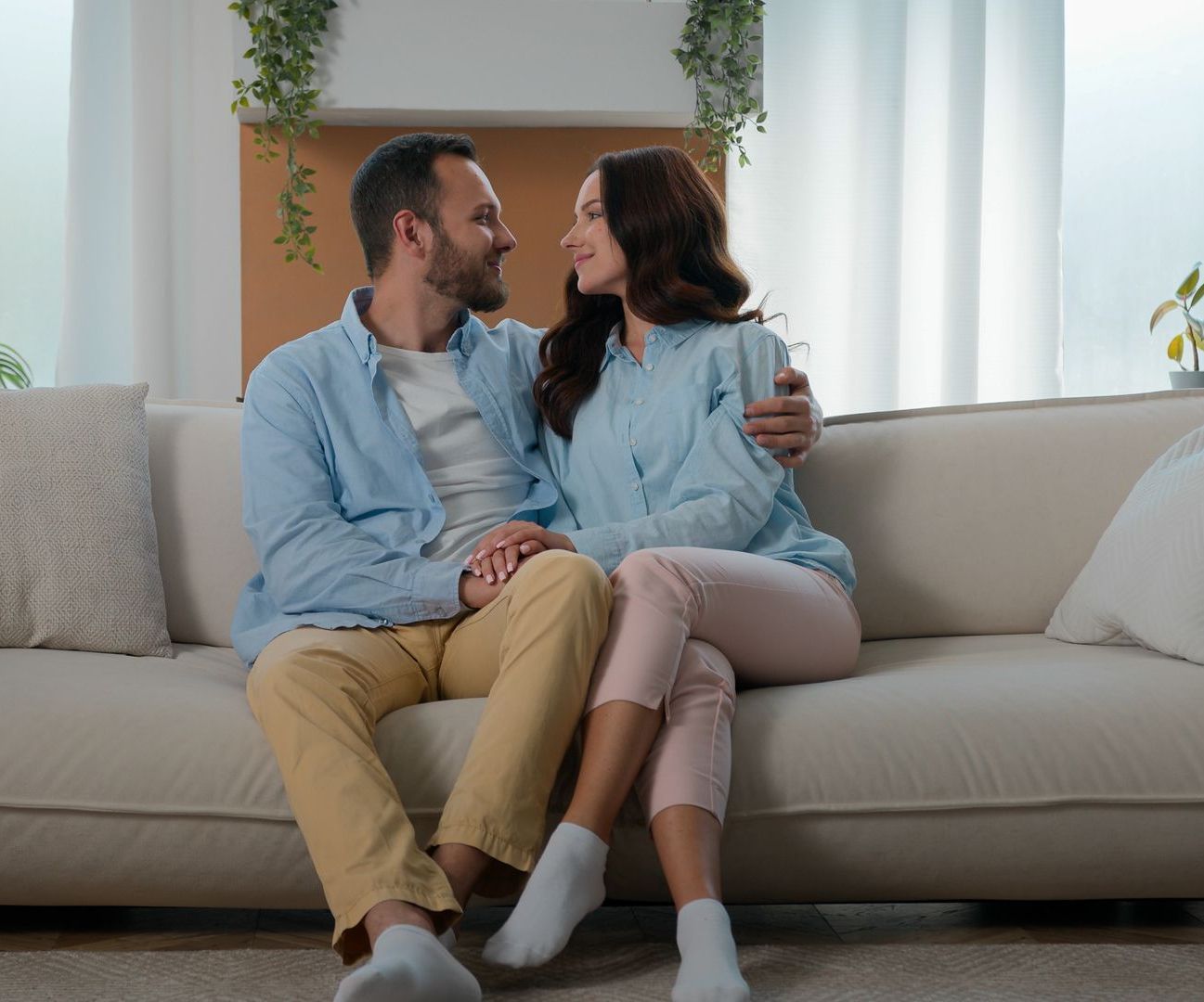 A man and a woman are sitting on a couch looking at each other.