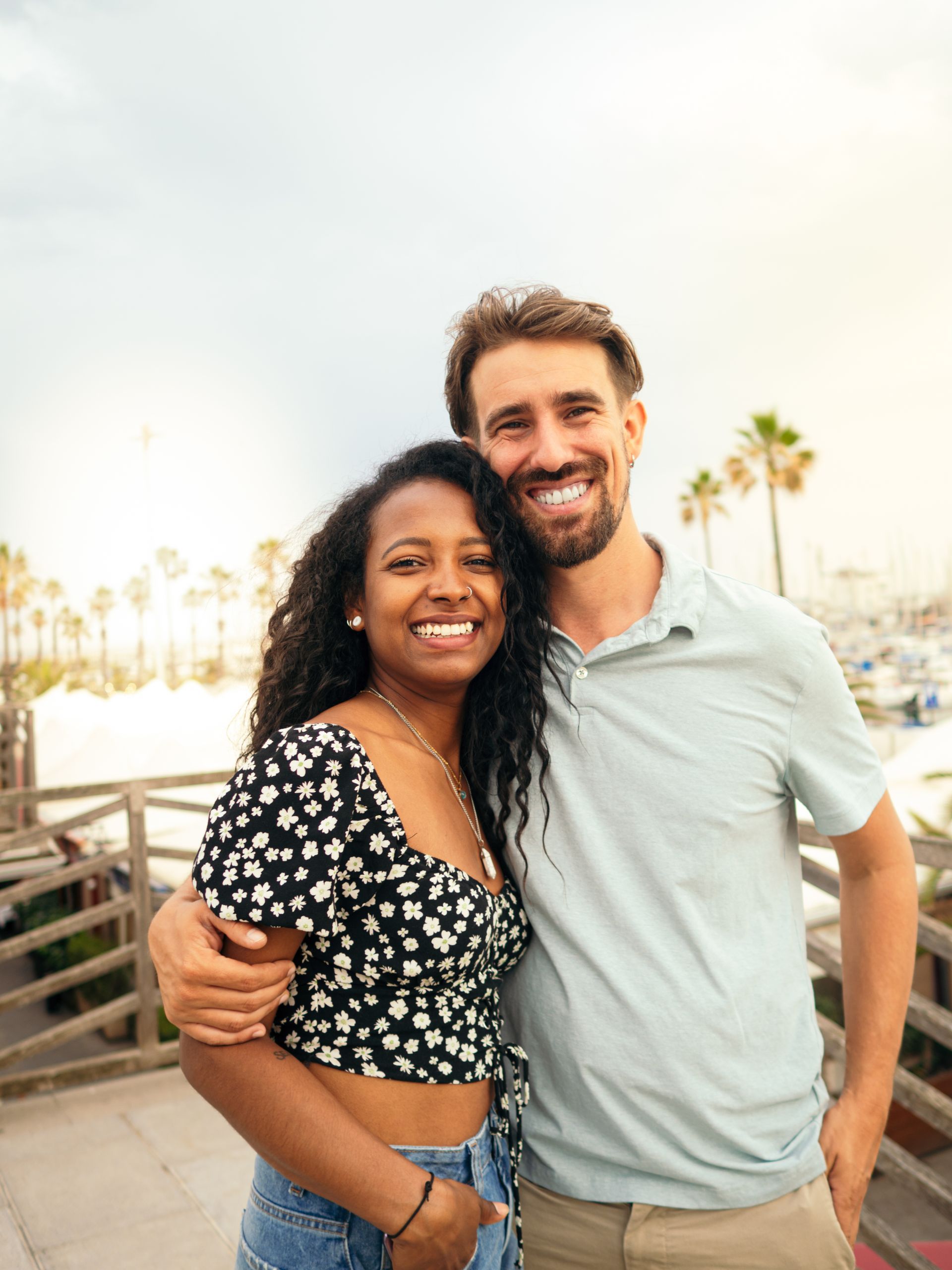A man and a woman are posing for a picture on a balcony.