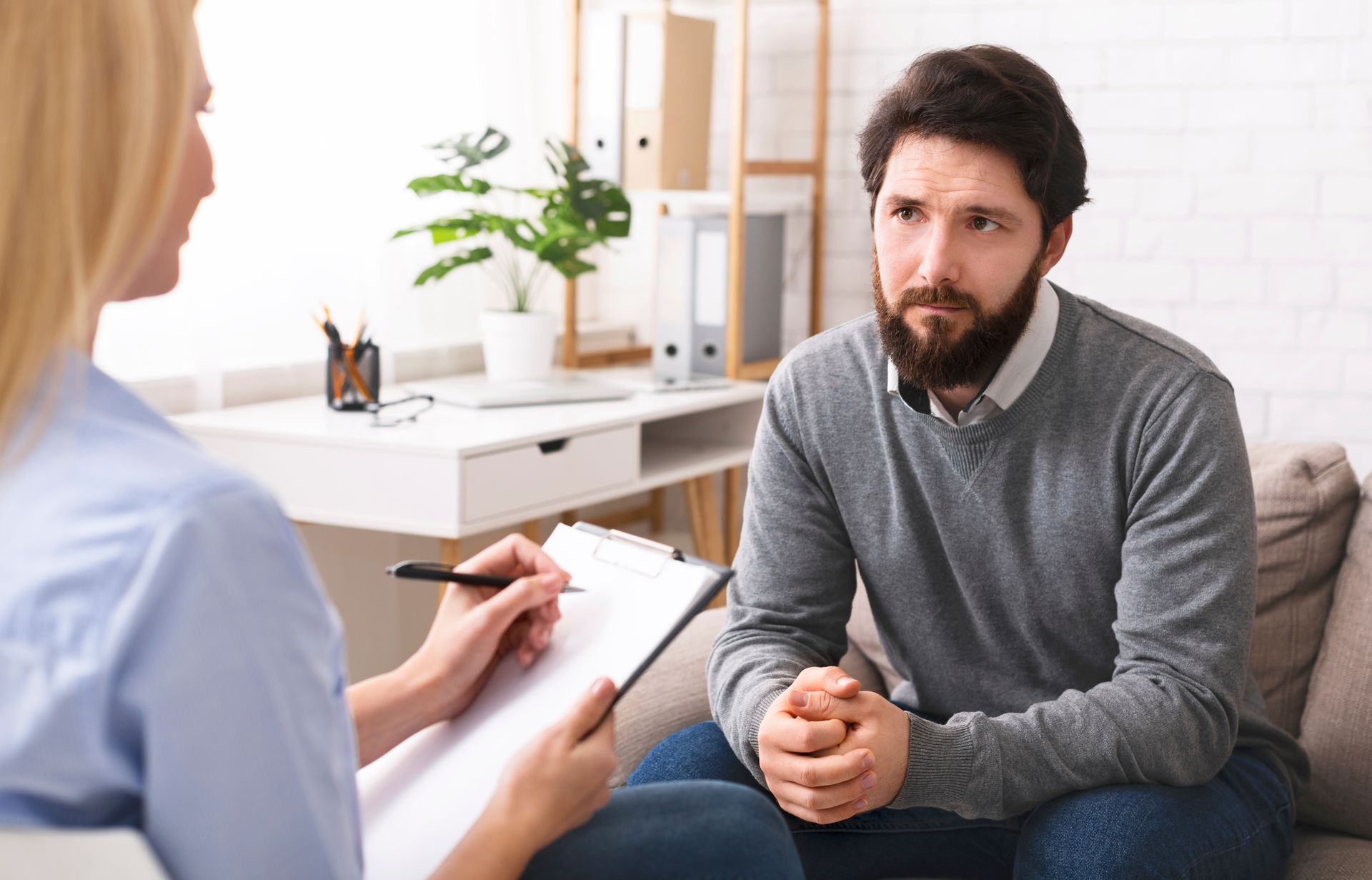 A man is sitting on a couch talking to a woman.
