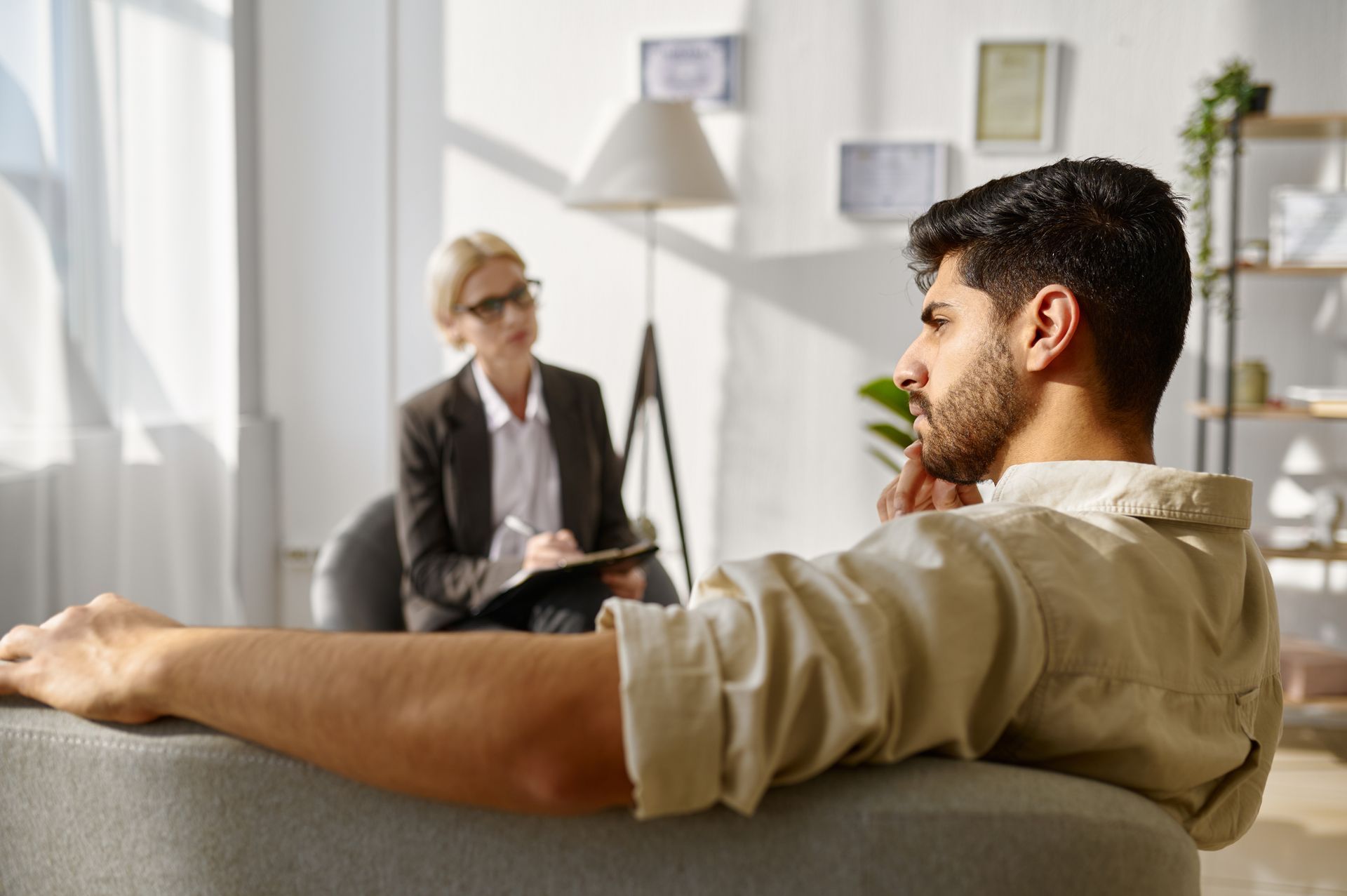 A man is sitting in a chair talking to a woman.