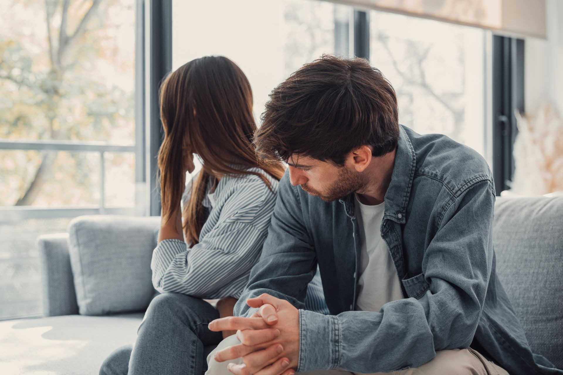 A man and a woman are sitting on a couch having an argument.
