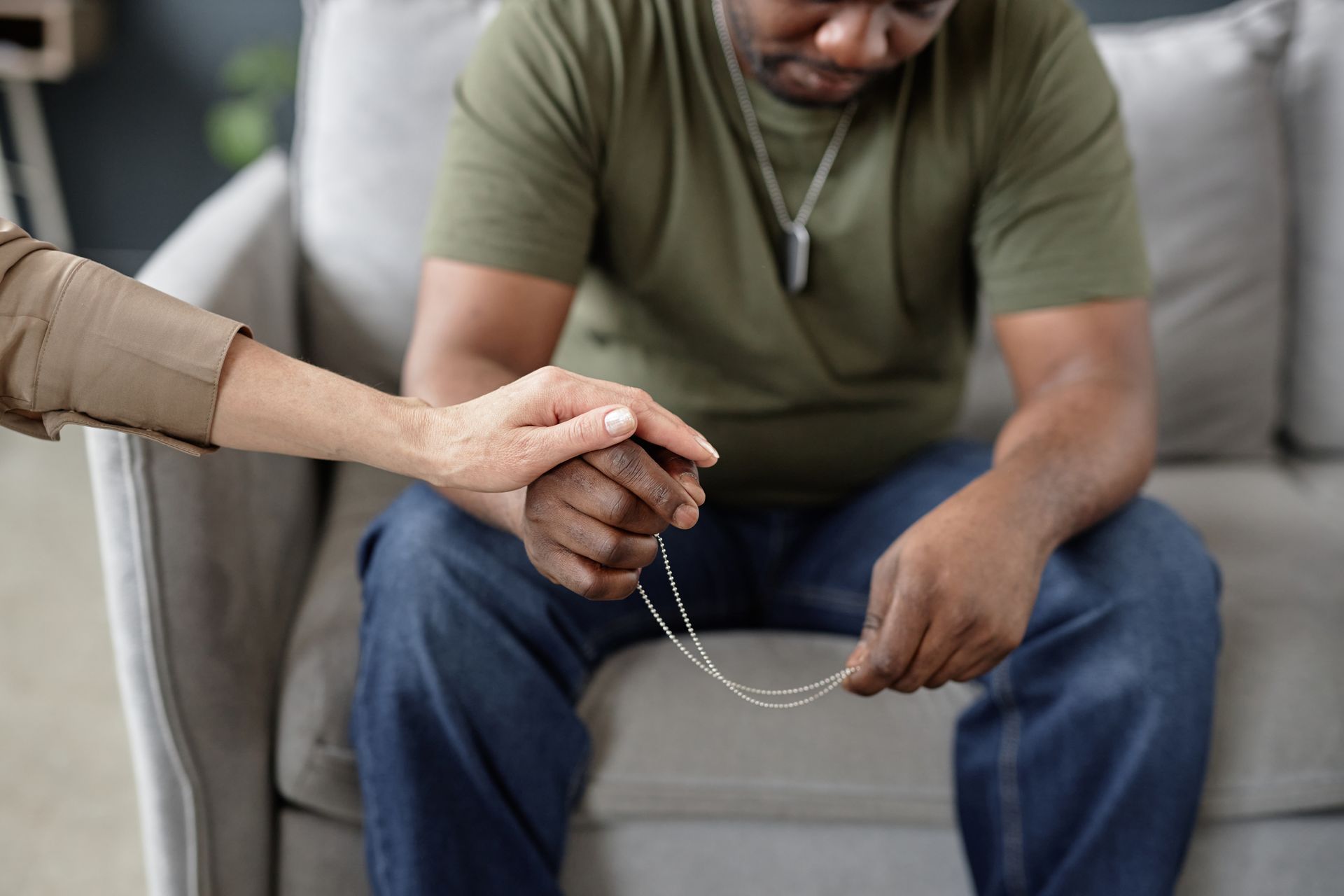 A woman is holding a man 's hand while sitting on a couch.