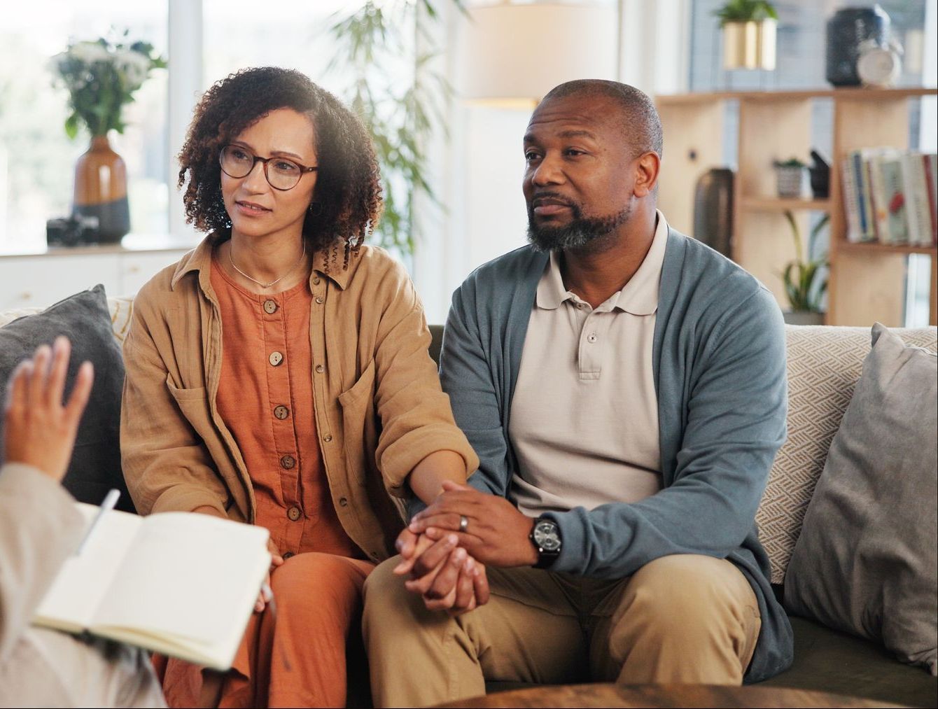 A man and woman are sitting on a couch talking to a woman.