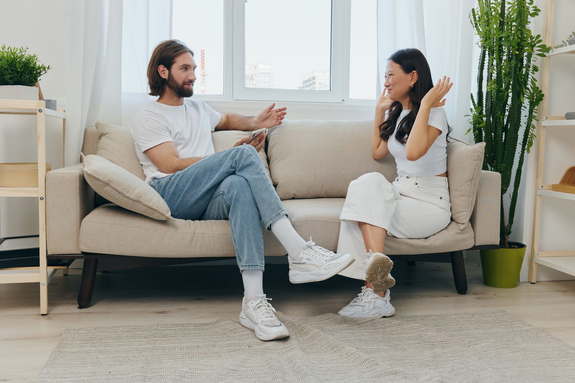 A man and a woman are sitting on a couch talking to each other.