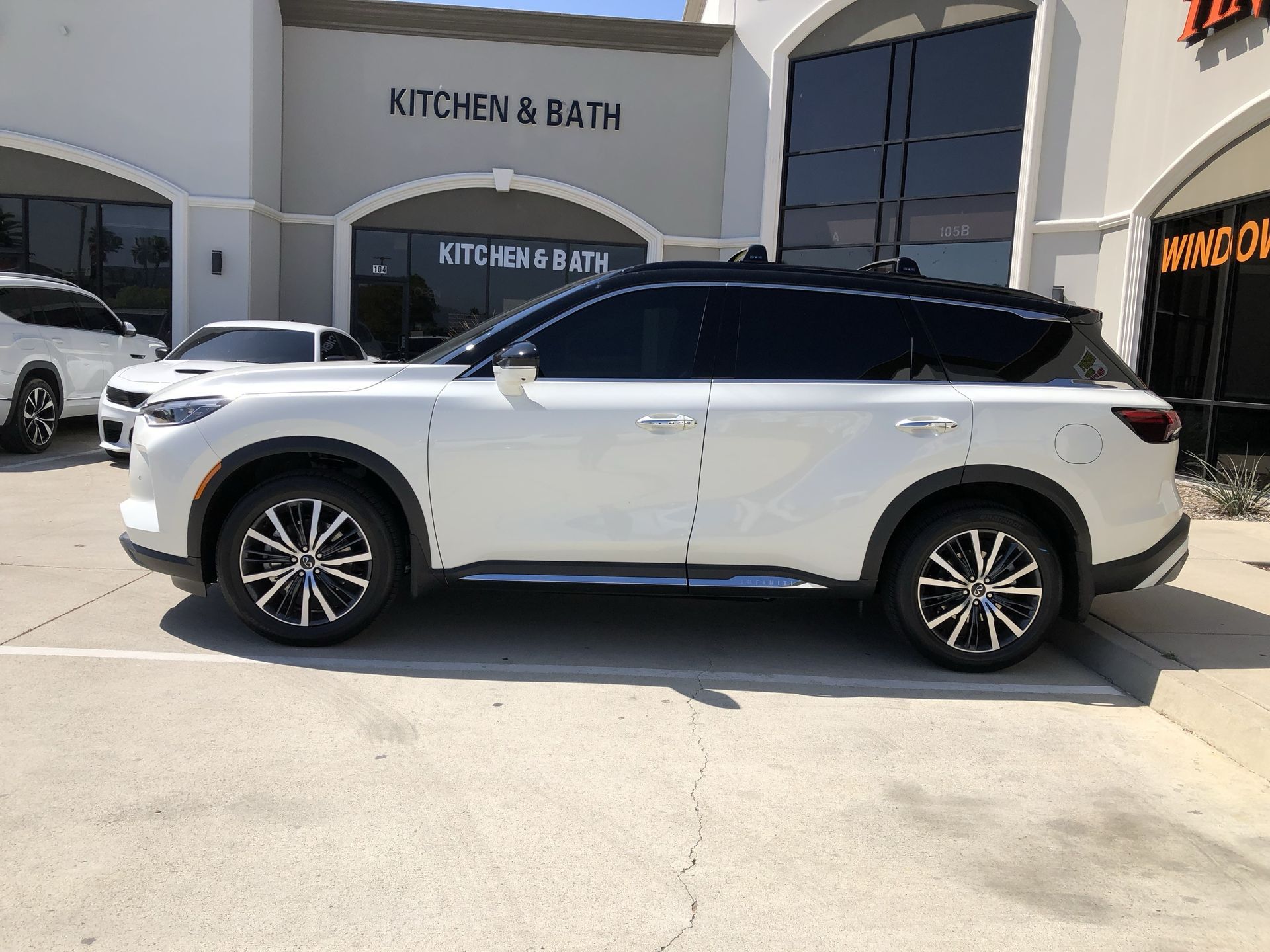 A white suv is parked in a parking lot in front of a building.