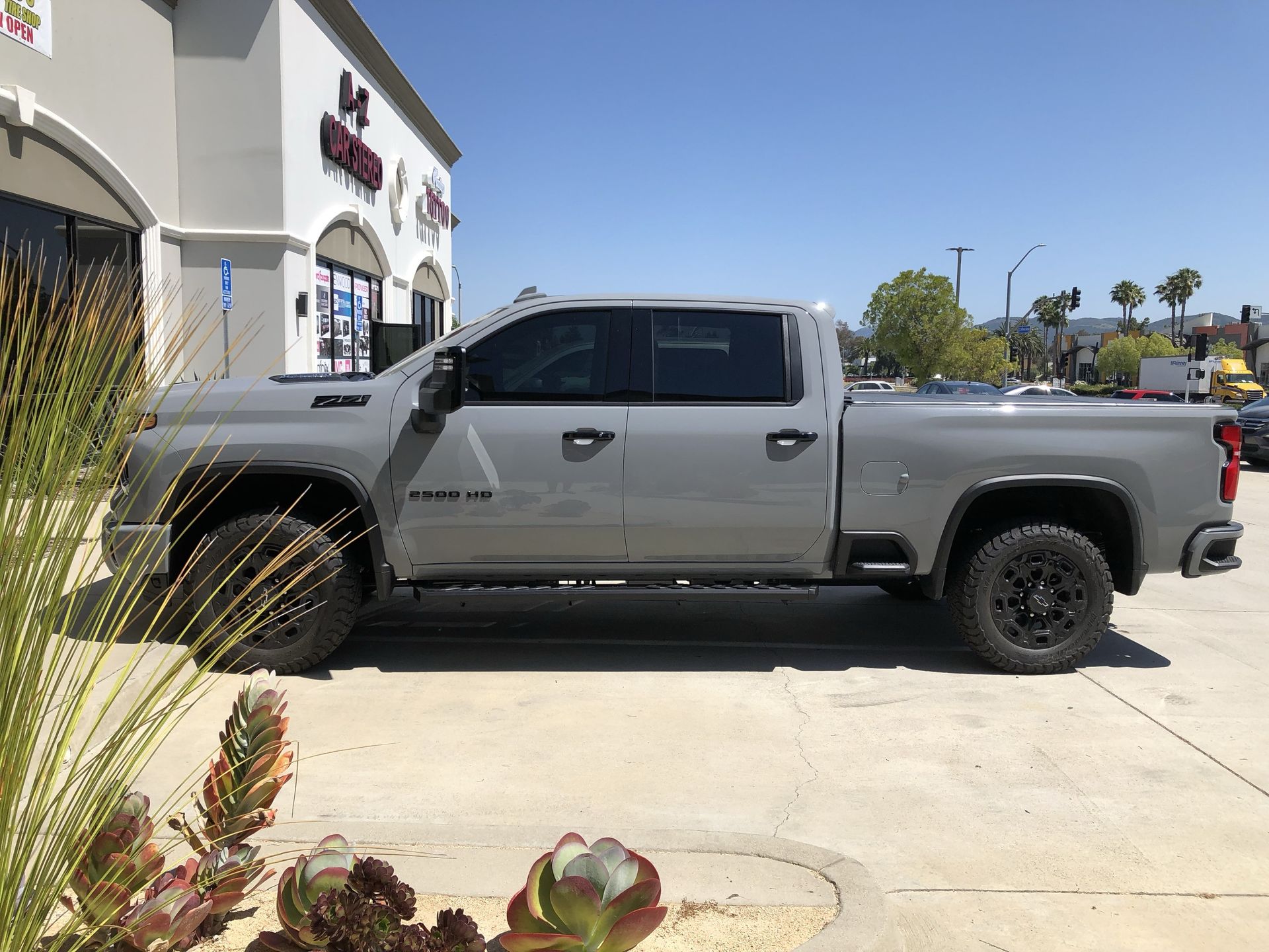 A gray truck is parked in a parking lot in front of a building.