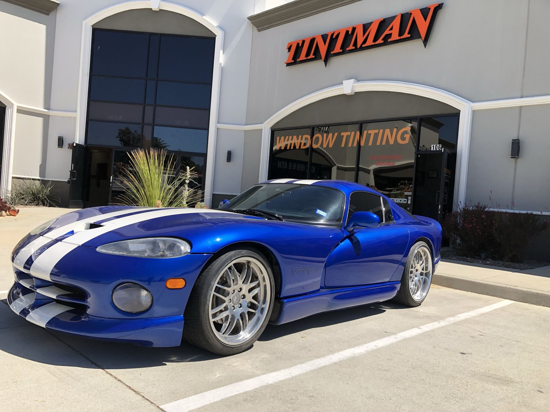A blue dodge viper is parked in front of a building.
