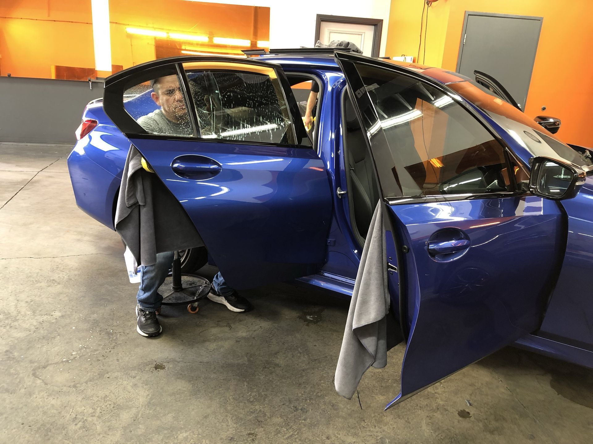 A man is working on a blue car in a garage.