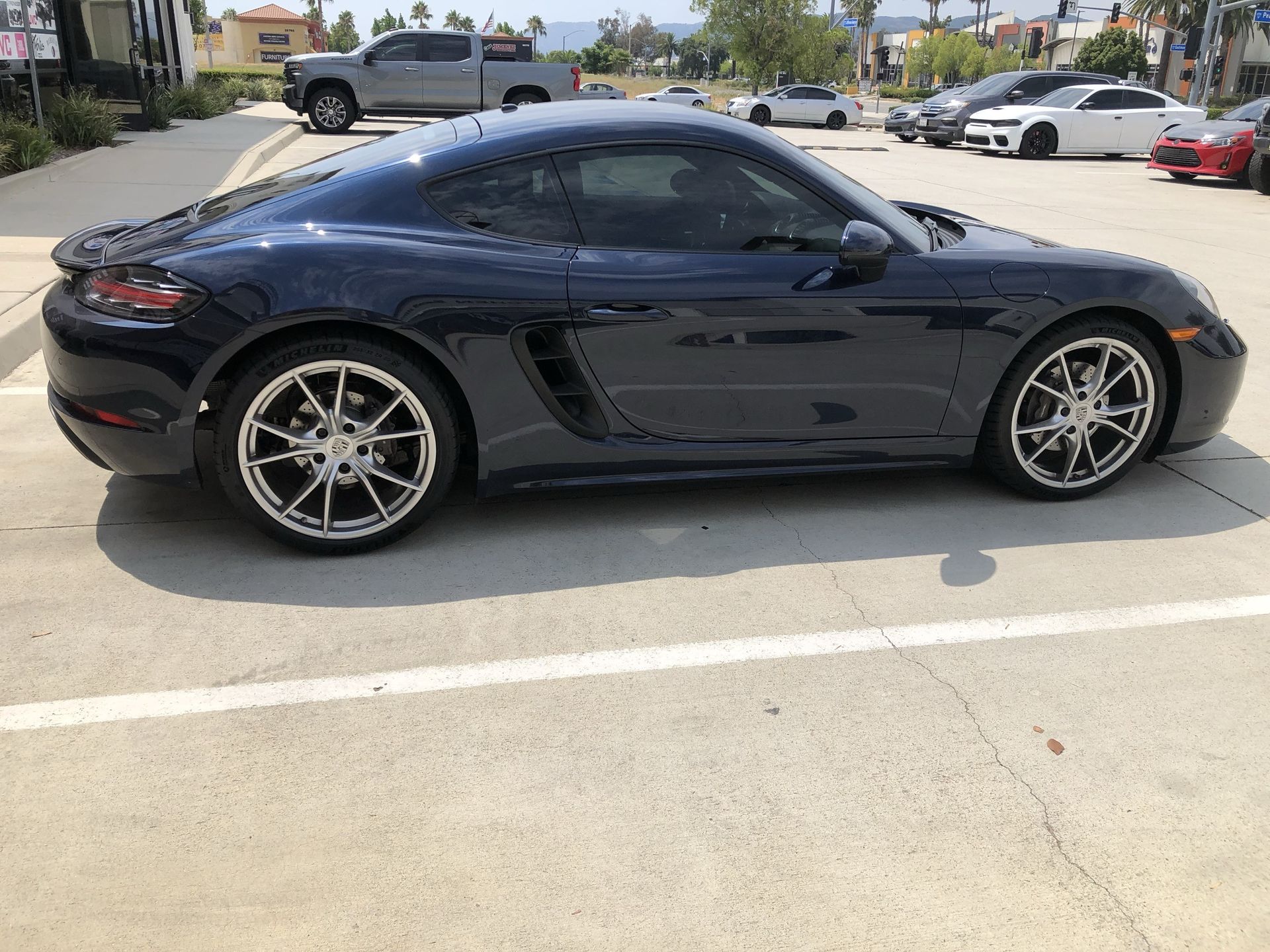 A black porsche boxster is parked in a parking lot.