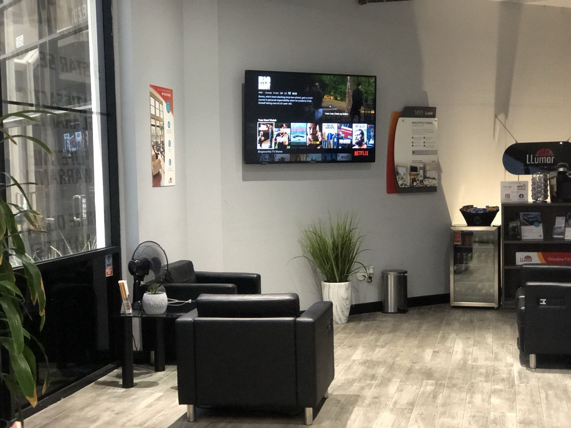 A living room with chairs and a flat screen tv on the wall.