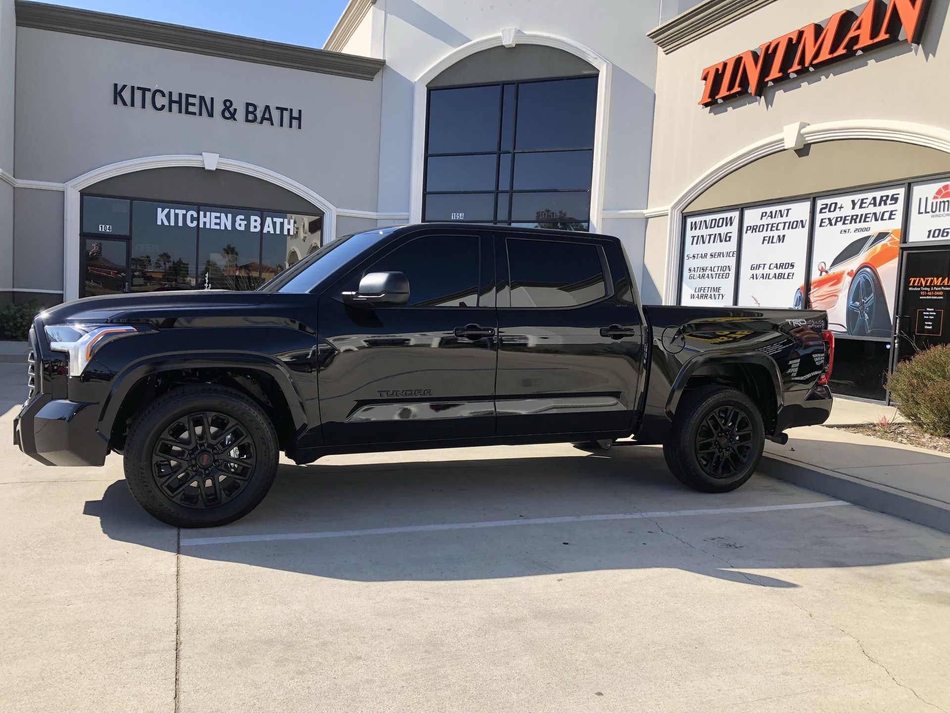 A black truck is parked in front of a kitchen and bath store.