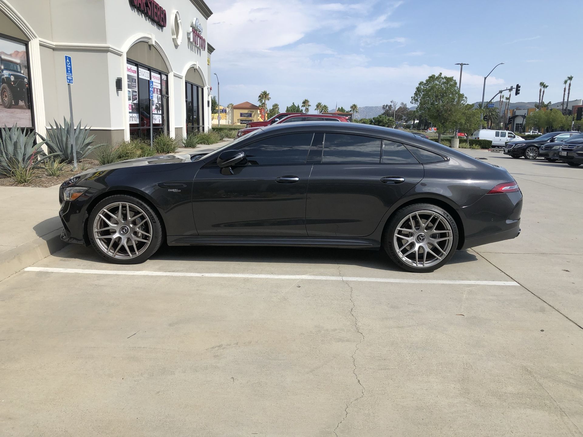 A black car is parked in a parking lot in front of a building.