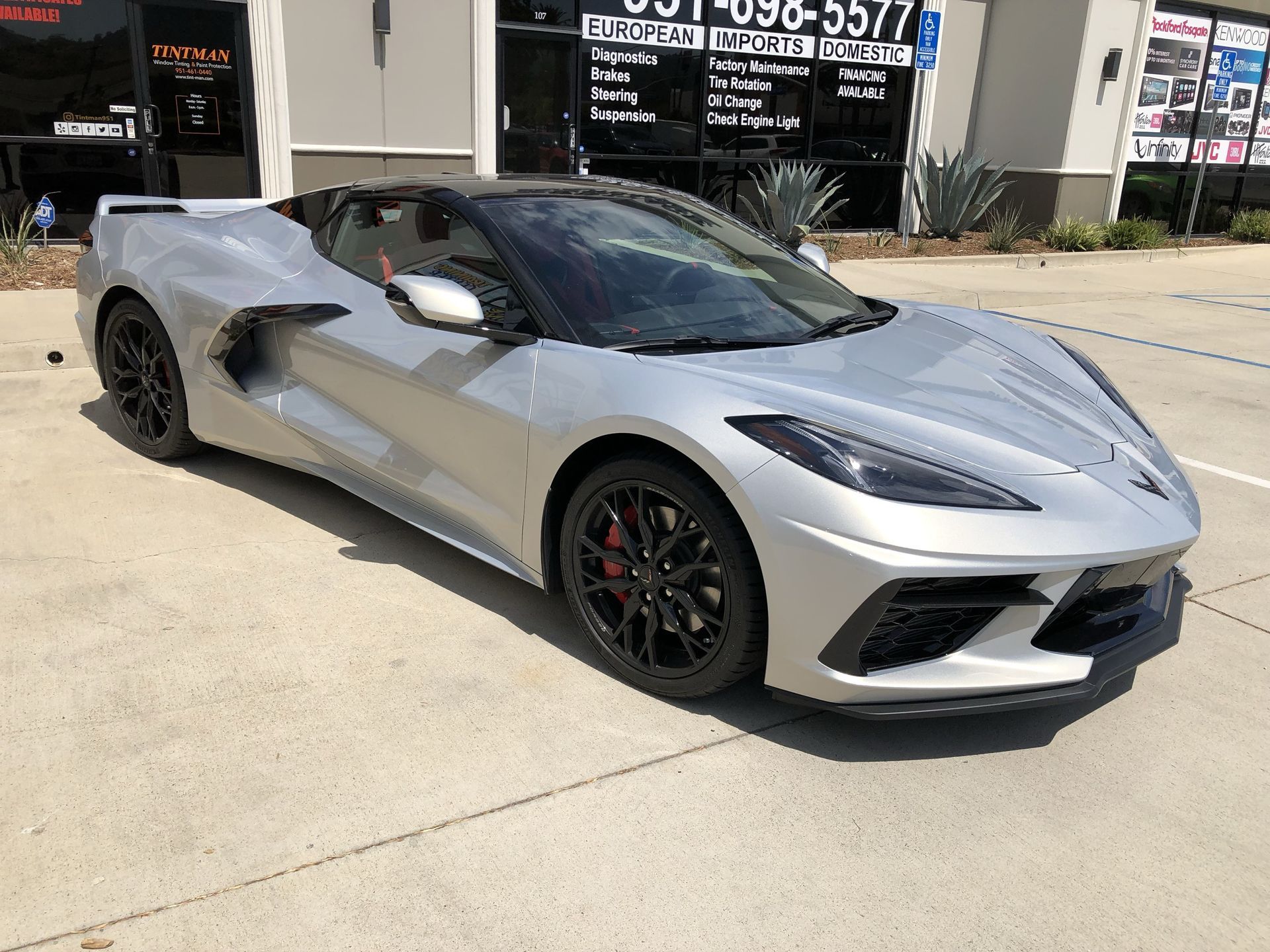 A silver sports car is parked in front of a building.