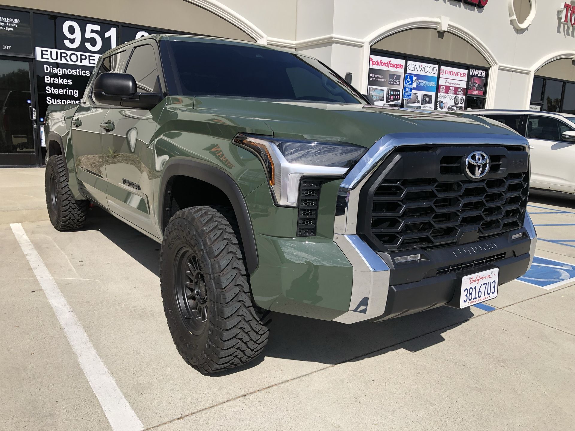 A green toyota tundra is parked in a handicapped parking spot.