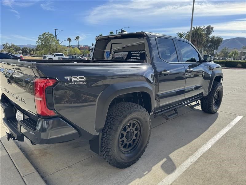 A black toyota tacoma truck is parked in a parking lot.