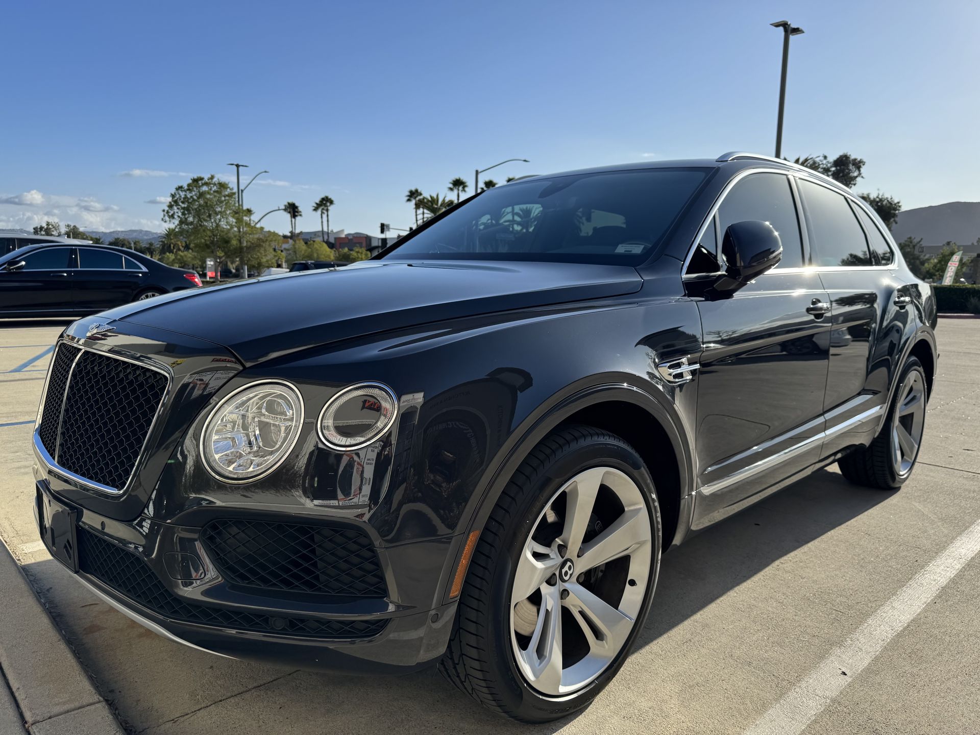 A black bentley is parked in a parking lot.