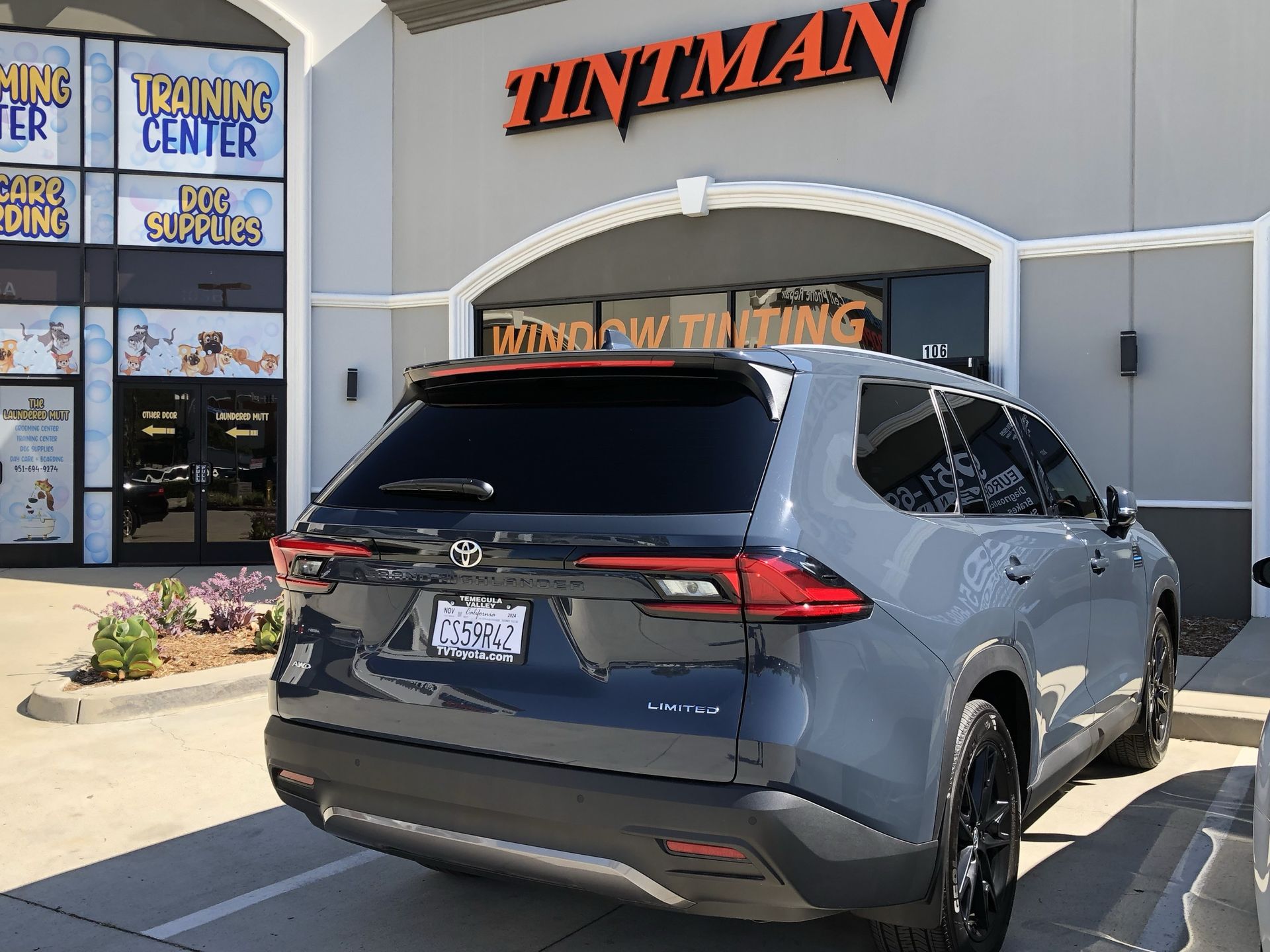 A car is parked in front of a building that says tintman