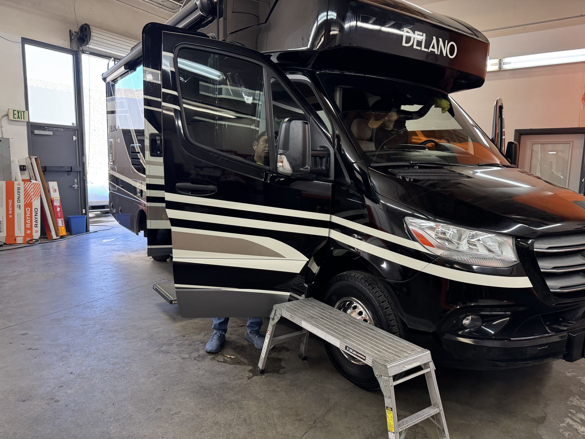 A black van is parked in a garage with its doors open.