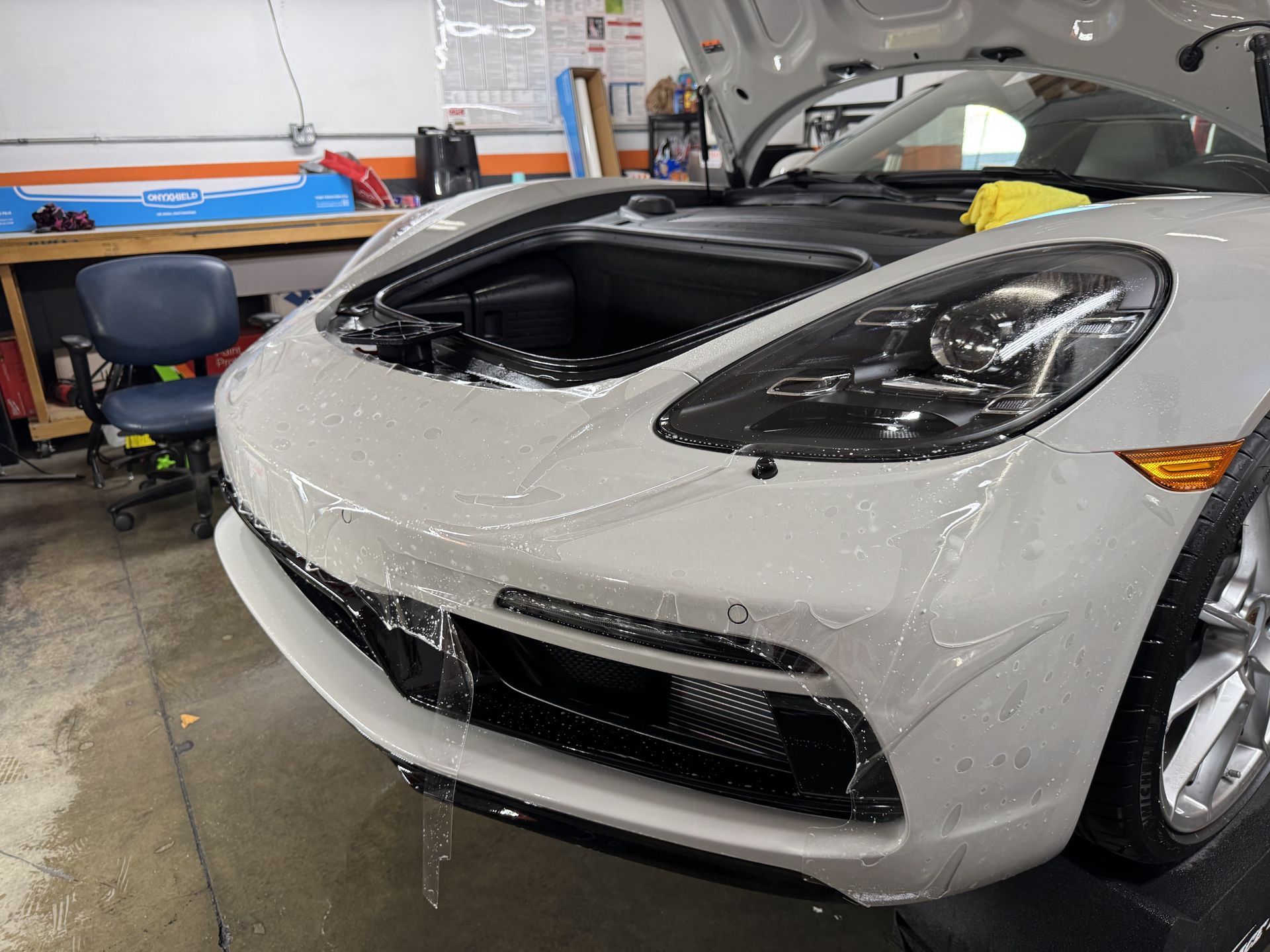A white sports car with the hood open in a garage