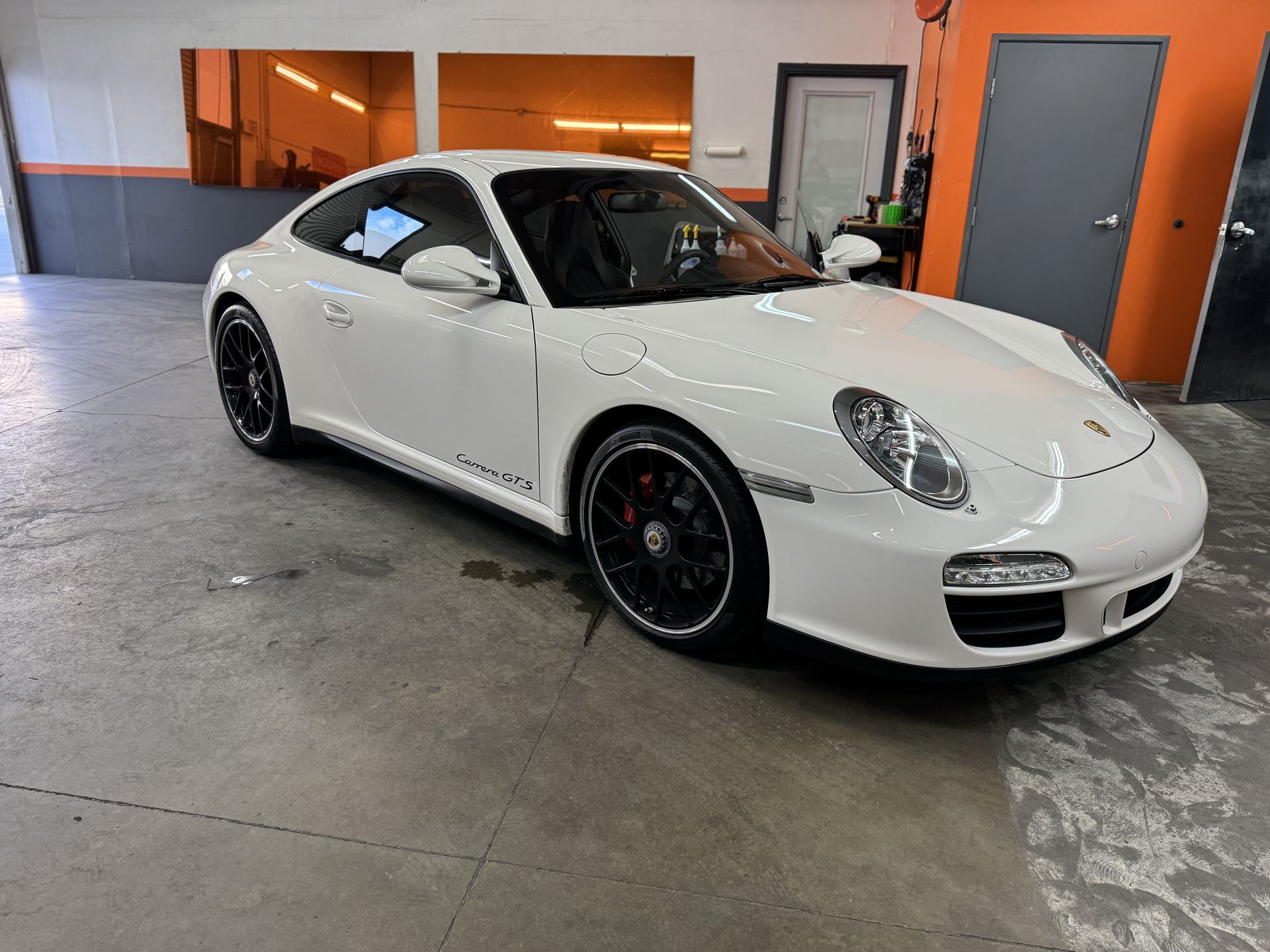 A white porsche 911 is parked in a garage.