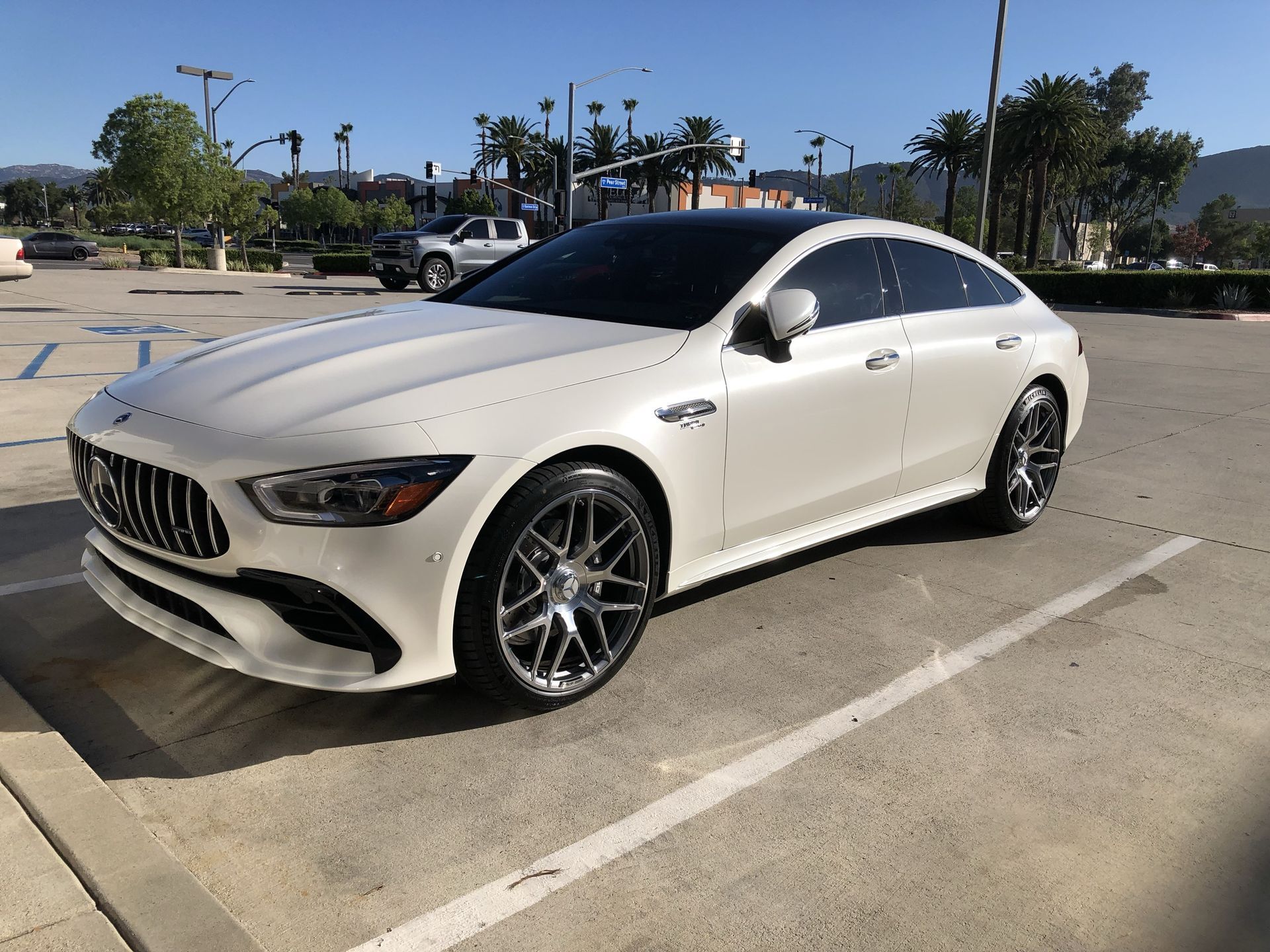 A white mercedes benz is parked in a parking lot.