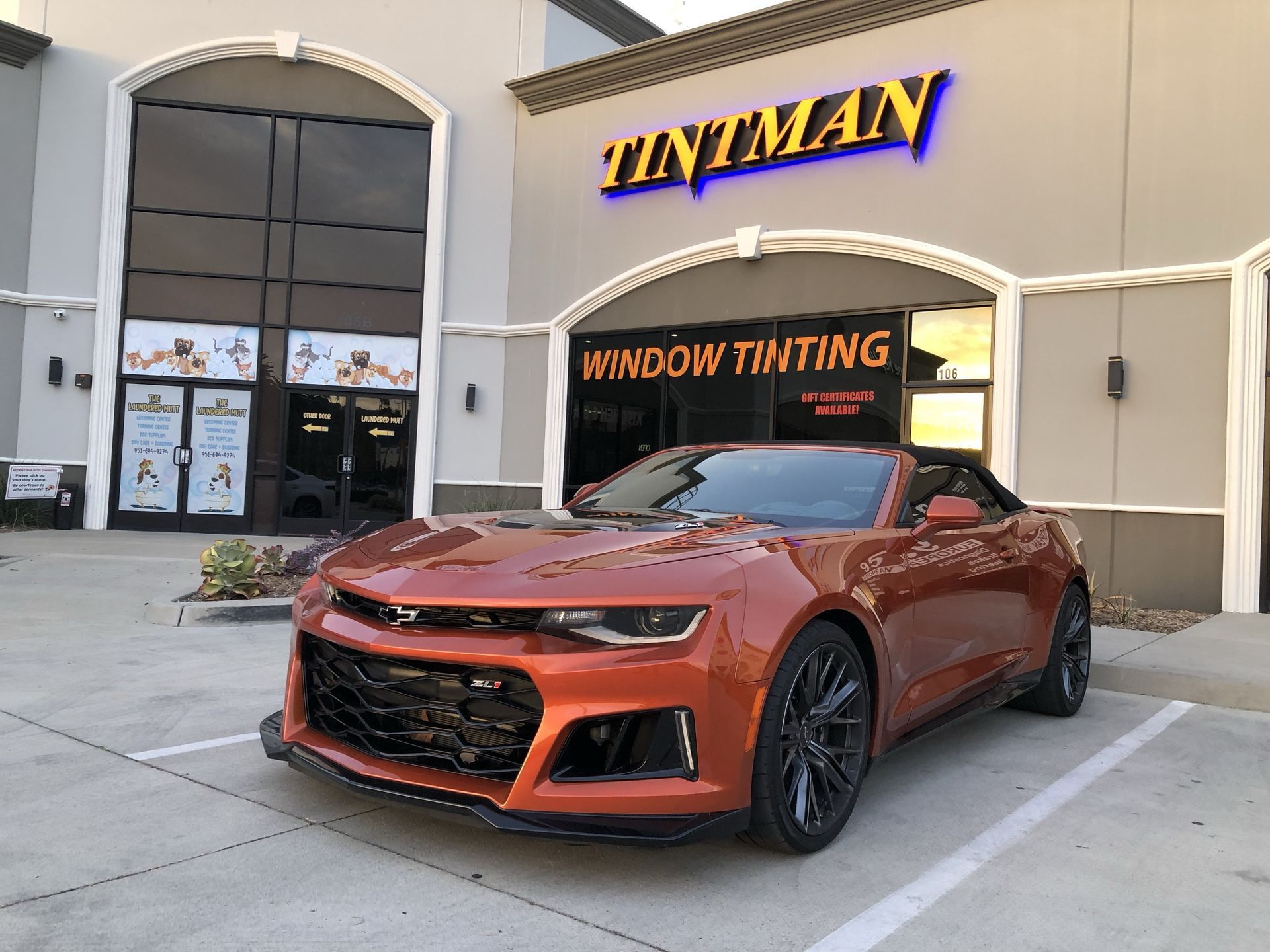 A car is parked in front of a tintman window tinting store.