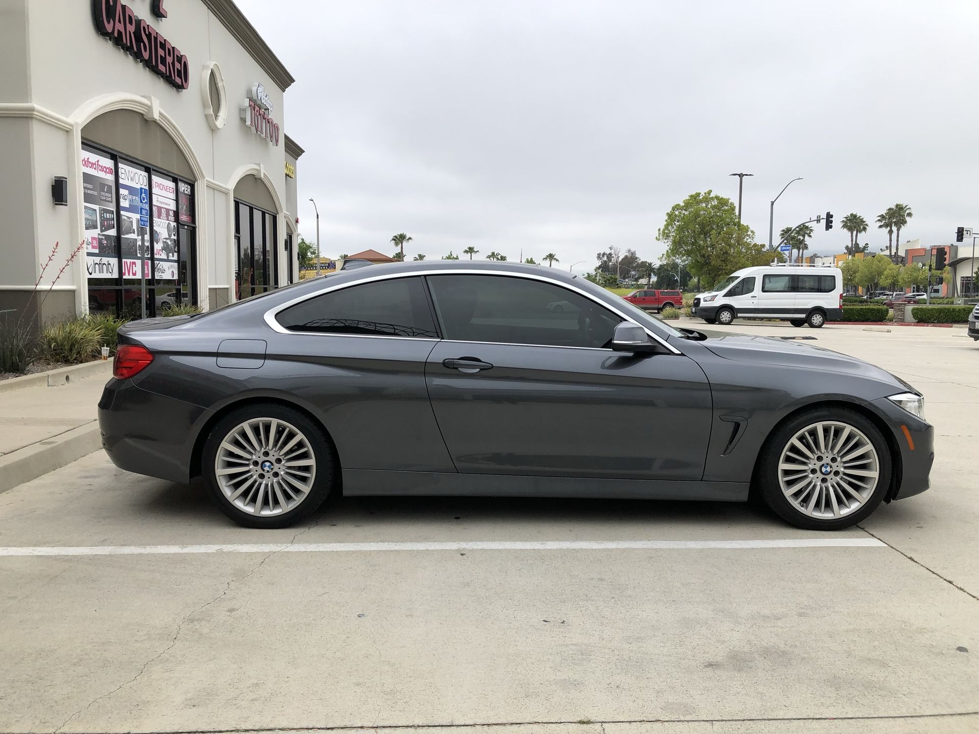 A gray bmw is parked in a parking lot in front of a building.
