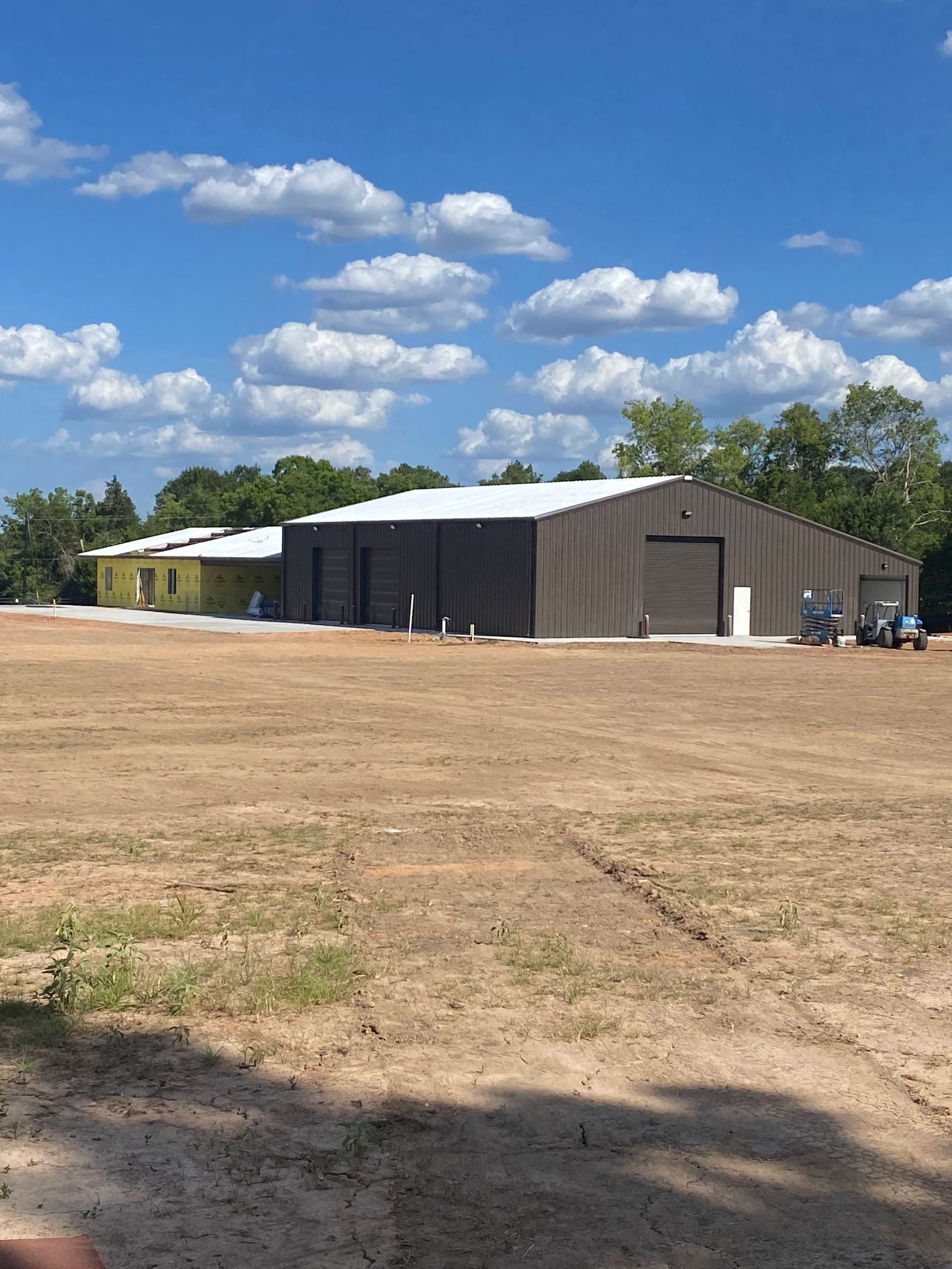 Brown metal industrial buildings with gray roll-up doors, white roofs, and clear blue sky.