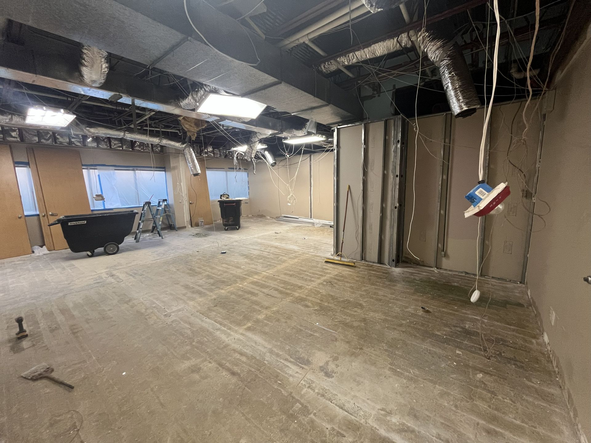 Renovated room interior with exposed walls, ductwork, and debris.