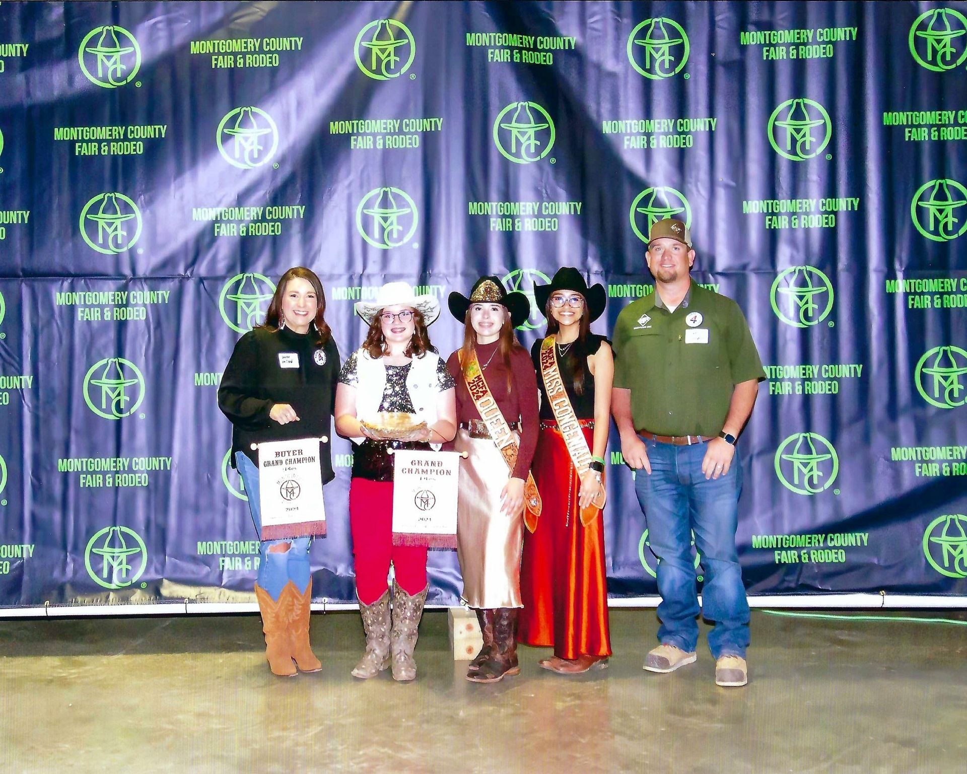 People in cowboy attire pose with awards in front of a backdrop with logos.