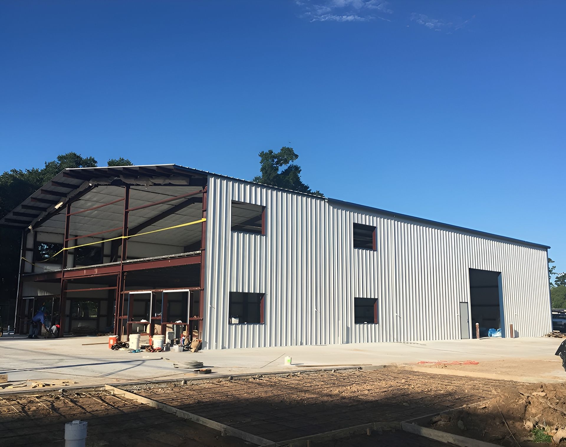 Steel-framed commercial building under construction with metal siding and open interior, under blue sky.