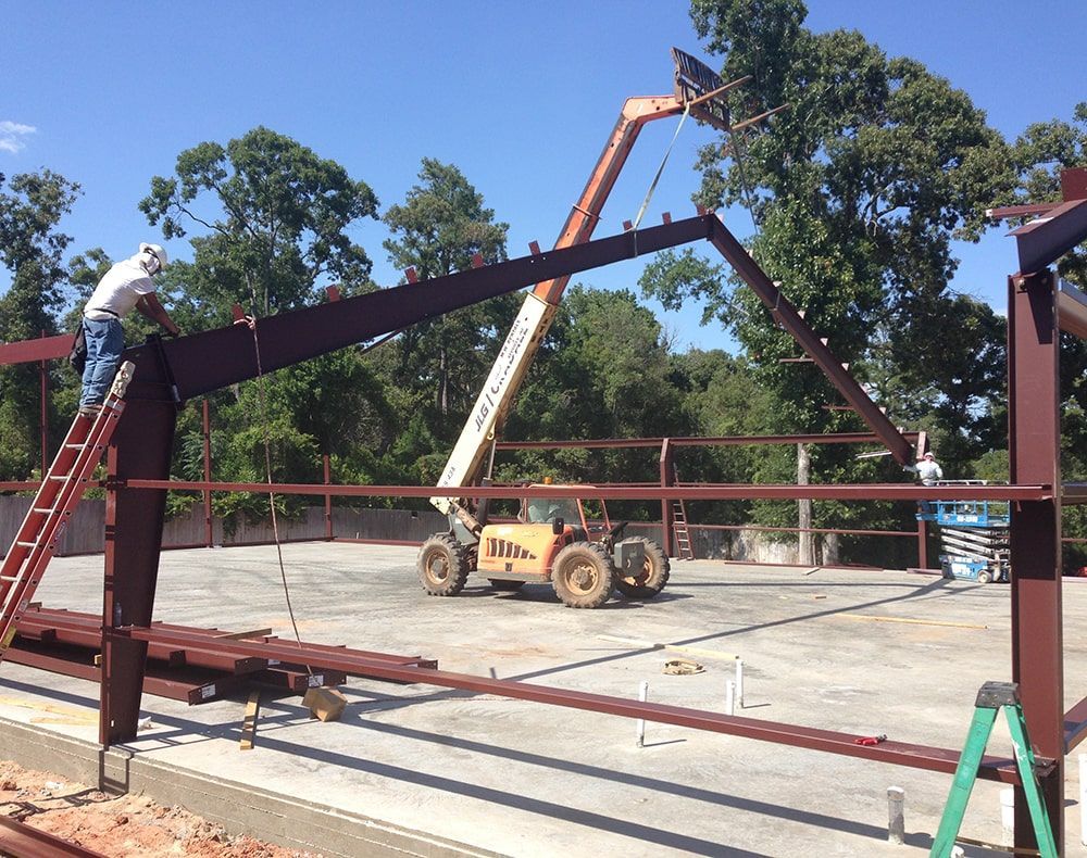 Construction workers installing steel beams for a building frame, using a lift. Sunny day.
