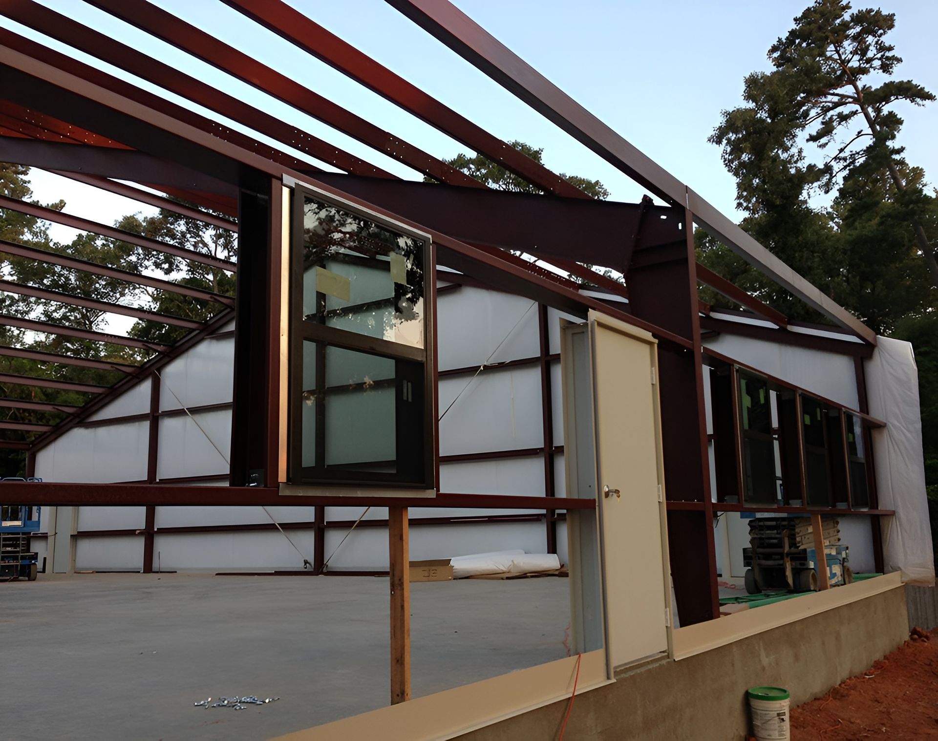Steel frame building under construction, windows installed. Beige door and white insulation are visible.