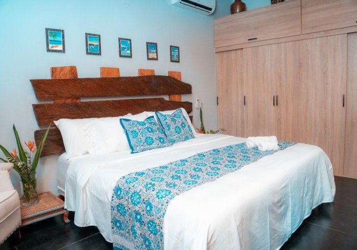Bedroom with a large bed, blue and white accents, wooden headboard, and built-in closet. Coastal decor with framed pictures.