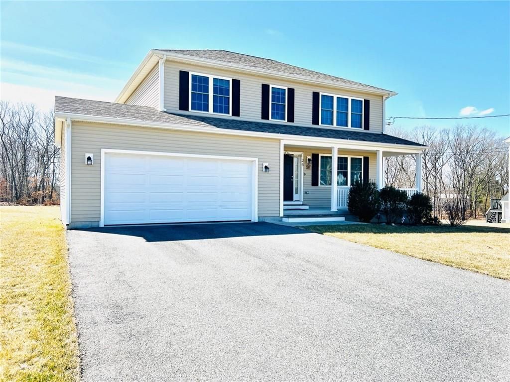 Two-story house with beige siding, a white garage door, and black shutters, set in a sunny, grassy lot.
