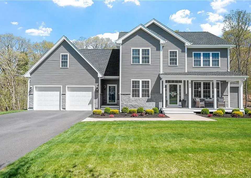 Two-story gray house with white trim, porch, two-car garage, and manicured lawn.