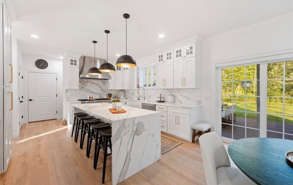 Living room with sofa, fireplace, blue floral rug, and white curtains.