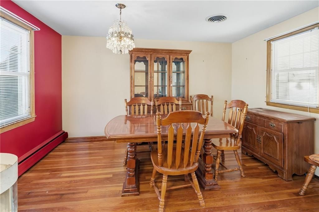 Dining room with wooden furniture, including table, chairs, hutch, and sideboard. Red and beige walls, chandelier.