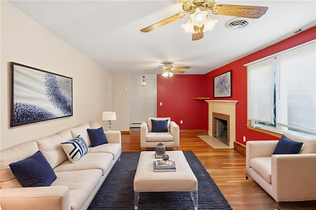Living room with a sofa, chairs, rug, fireplace, and wood floors.