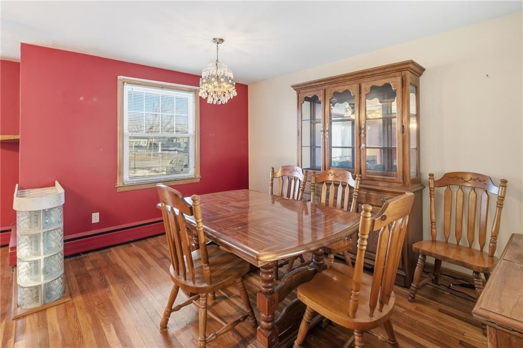 Dining room with wooden table and chairs, red wall, window, and cabinet.