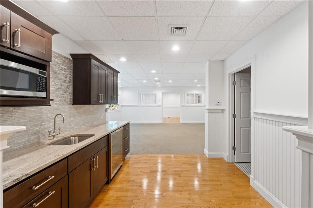 Kitchen with brown cabinets, stainless steel appliances, and wooden floor. White walls and ceiling.