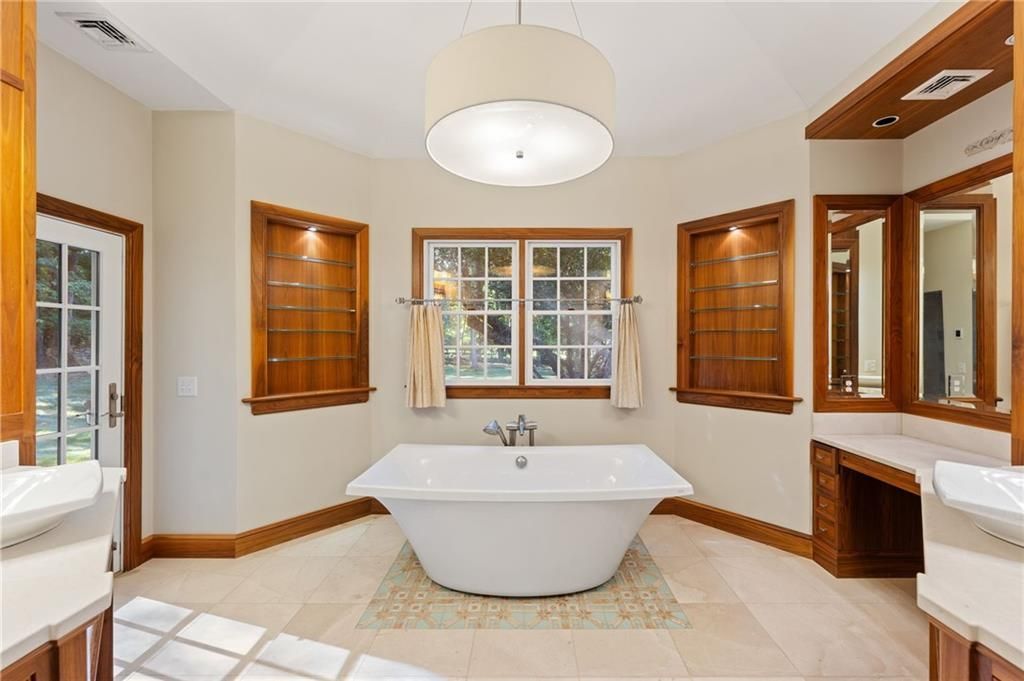 Bathroom with a white freestanding tub centered under a window with wooden trim and accents.