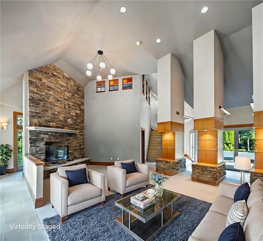 Spacious living room with stone fireplace, high ceilings, and modern furniture.