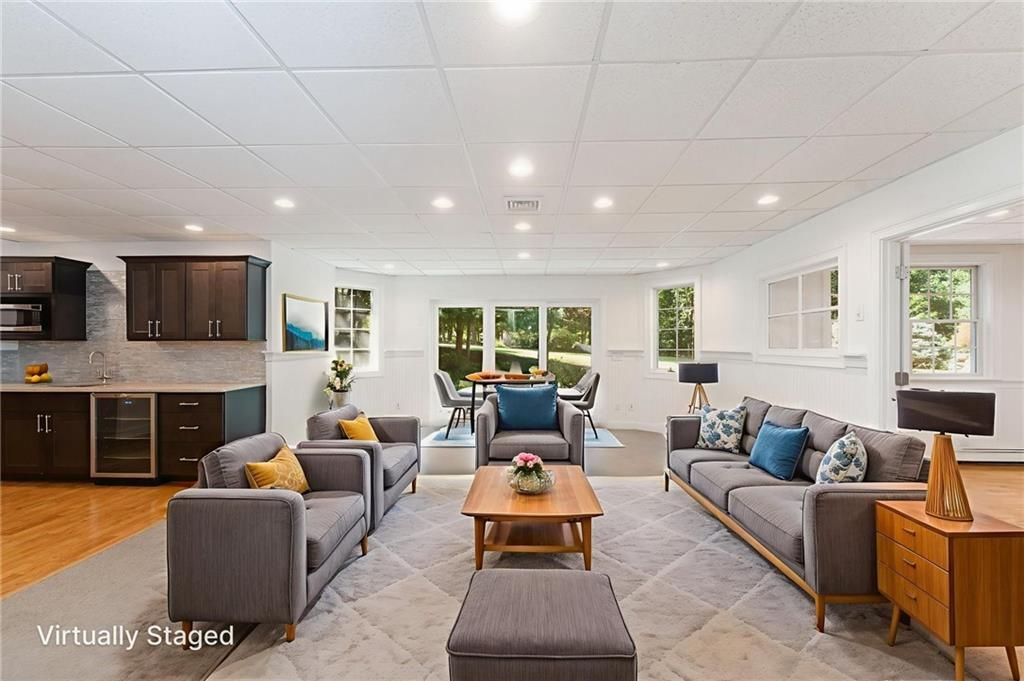 Modern living room with gray sofas, a wooden coffee table, and a small kitchen area.