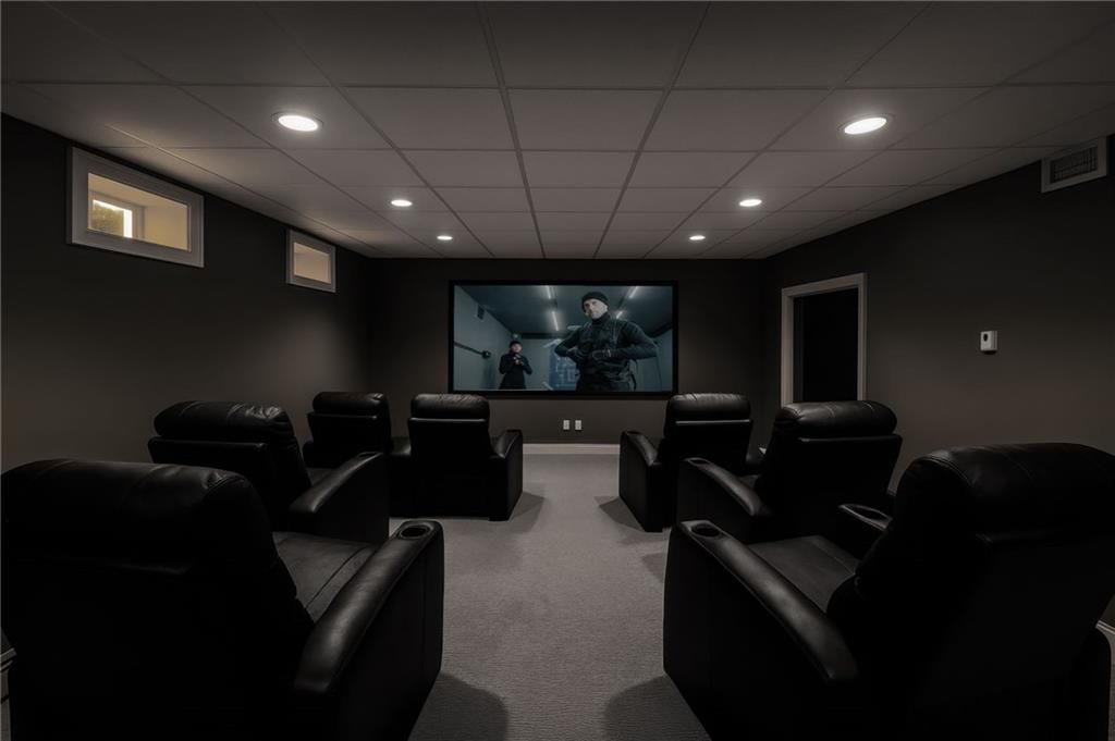 Home theater room with reclining chairs facing a large screen displaying a movie.