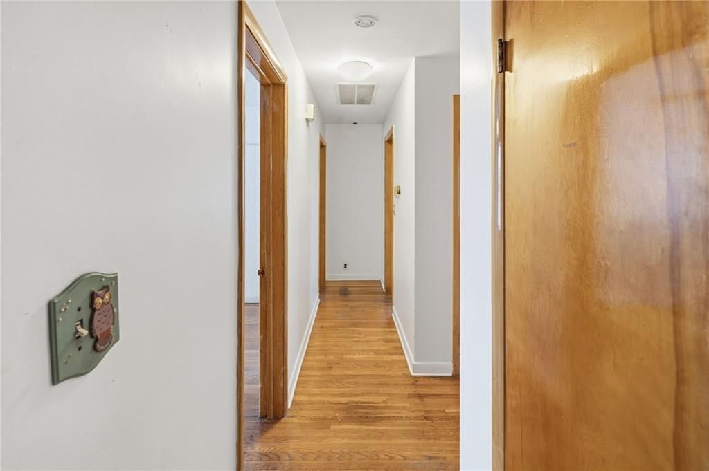 Hallway with wooden floors, white walls, and open doors.