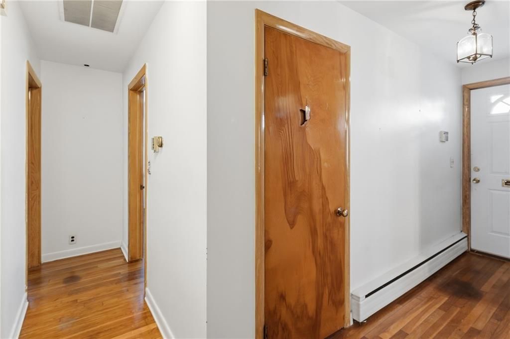 Hallway with wooden doors, white walls, and wood floor.