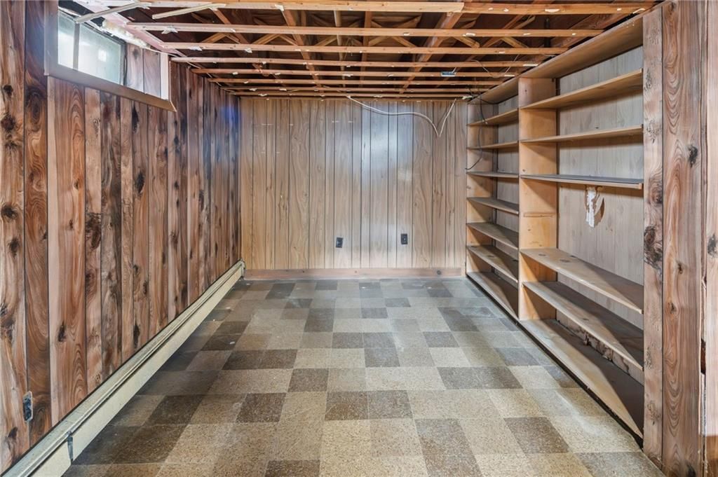 Empty room with wood paneling, built-in shelves, and checkered flooring.