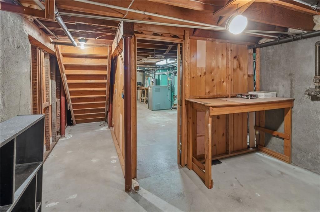 Basement interior with unfinished wood paneling, concrete walls, and a work table.