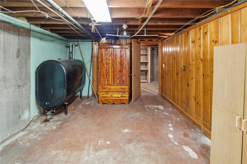 Basement with oil tank, wood paneling, and concrete floor.